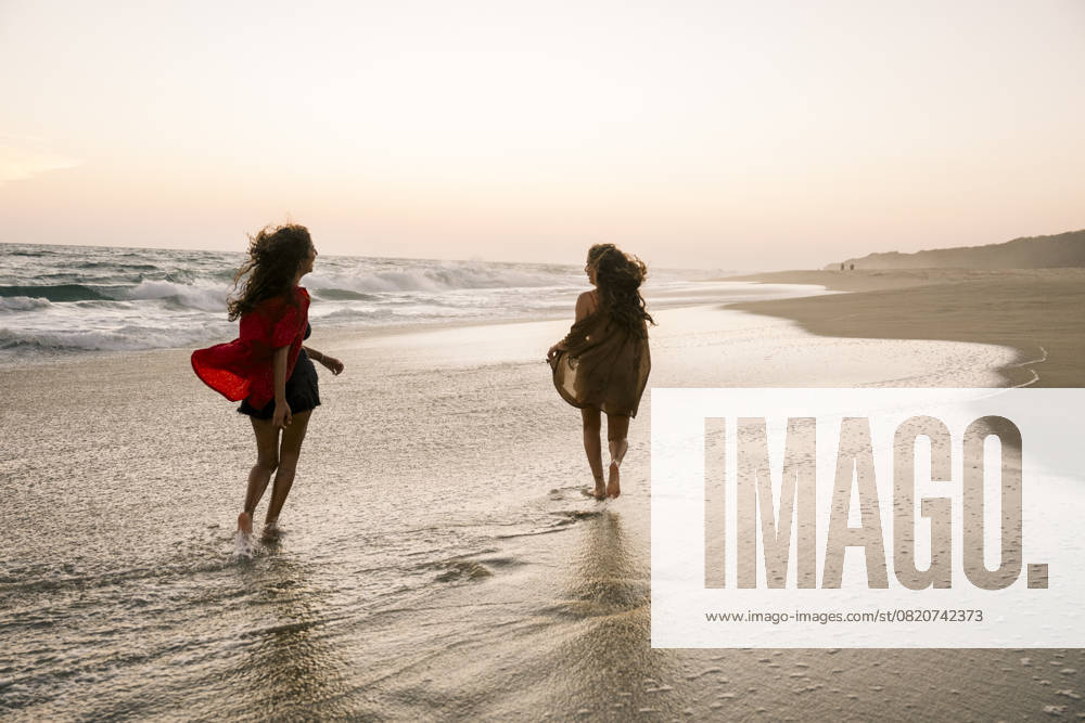 Two women running on the beach at sunset enjoying their holiday model released, Symbolfoto property released, FLMZF00545