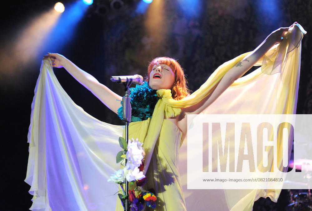 Florence and The Machine Live at The Greek Florence Welch of Florence & The Machine performs live at The Greek Theatre in Los Feliz, California, USA, June 13th 2011. music on stage concert gig performing half length yellow dress teal blue flower oversized corsage tattoo arm strapless cloak silk sheer bow tied high neck microphone singing mouth open arms outstretched flowers stand raised up CAP DVS DVS Los Feliz California United States