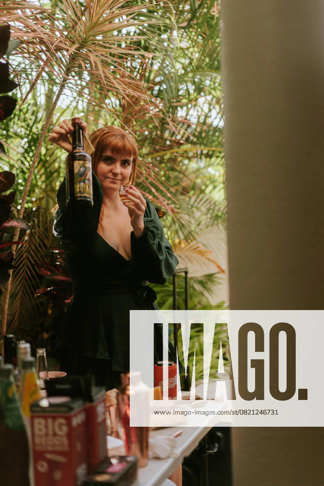 IMAGO Creative, Lifestyle, Feste im Garten #2 Woman showing bottle and shot glass at garden party Sunshine Coast, Queensland, Australia R_YUKI250529B-1697873-01