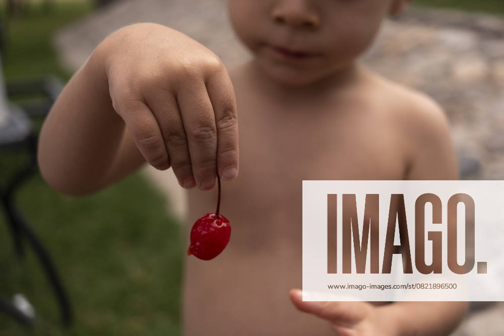 IMAGO Creative, Jahreszeit Sommer, Kirschen Child Holding a Maraschino Cherry San Miguel de Allende, Guanajuato, Mexico R_WDJM250522-1736478-01 ,model released, Symbolfoto