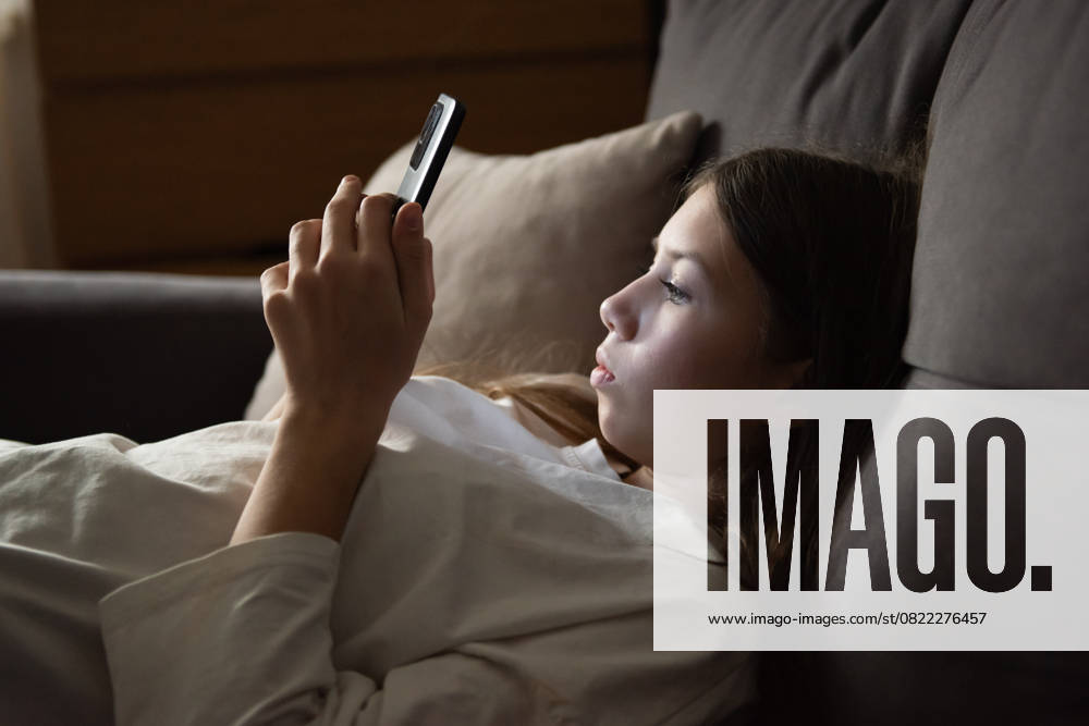 Ein trauriges Teenager-Mädchen liegt mit einem Smartphone in der Dunkelheit. Traurigkeit, Probleme. Das Konzept der Kurzsichtigkeit. A sad teenage girl is lying with a smartphone in the dark. Sadness, problems. The concept of myopia. (License=RF) ,model released, Symbolfoto