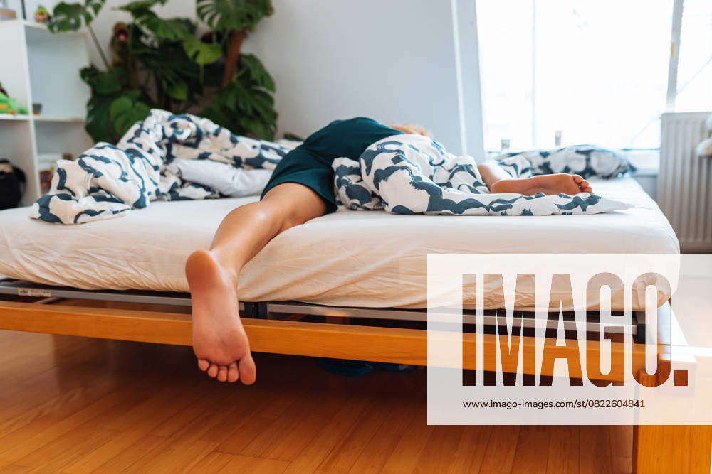 Junge frau liegt auf dem bett mit nackten füßen, die von einer decke bedeckt sind. füsse nahaufnahme sleeping young woman lies on bed with bare feet uncovered by blanket. feet close up (License=RF) ,model released, Symbolfoto