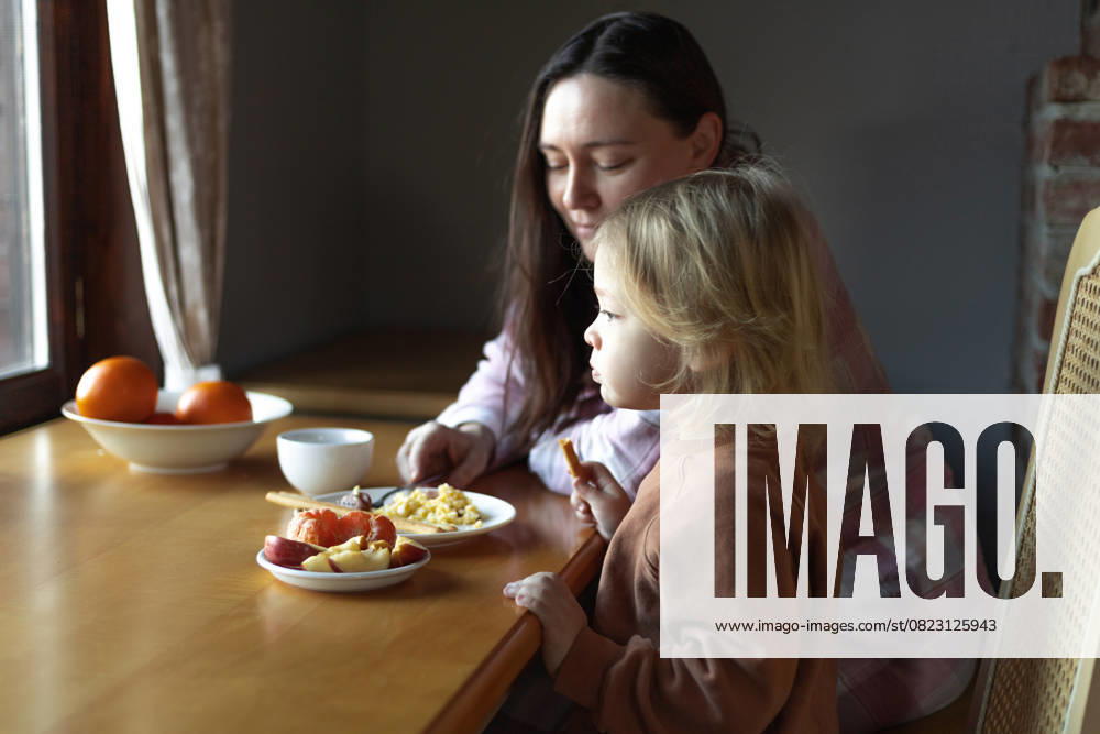 Woman and a boy are having breakfast at a table in front of a window Bukovynka, Lviv Oblast, Ukraine R_DCGM250623-1770576-01 ,model released, Symbolfoto