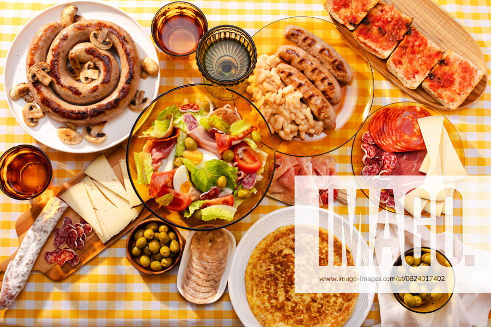 IMAGO Creative, Food, Tapas A vibrant table spread with a traditional Catalan salad, botifarra with mushrooms, olives, spanish jam, cheese, and a tortilla with potatoes Model Released MariaShchipakina_ID29079_888164_001