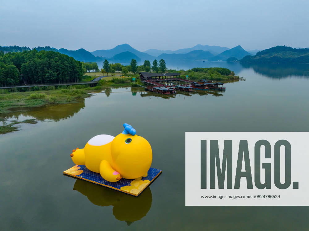 KW28 HANGZHOU, CHINA - JULY 08: Aerial view of an inflatable doll of Nailoong, also known as Milk Dragon, lying leisurely in the middle of a lake at Qingshan Lake National Forest Park on July 8, 2025 in Hangzhou, Zhejiang Province of China.