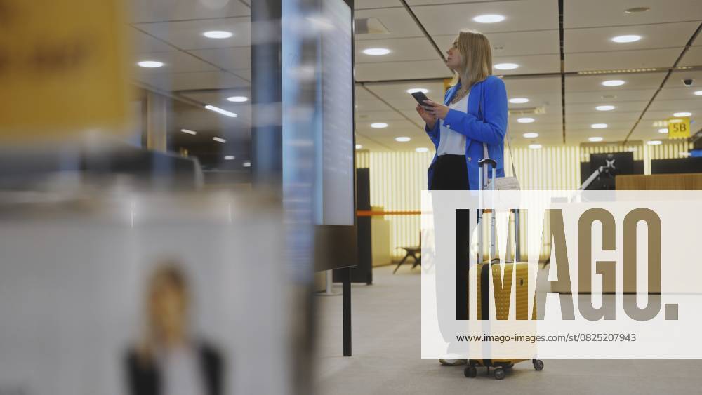 Frau im Geschäftsanzug bei der Kontrolle ihres Fluges im Flughafen Woman in business suit in checking her flight in airport