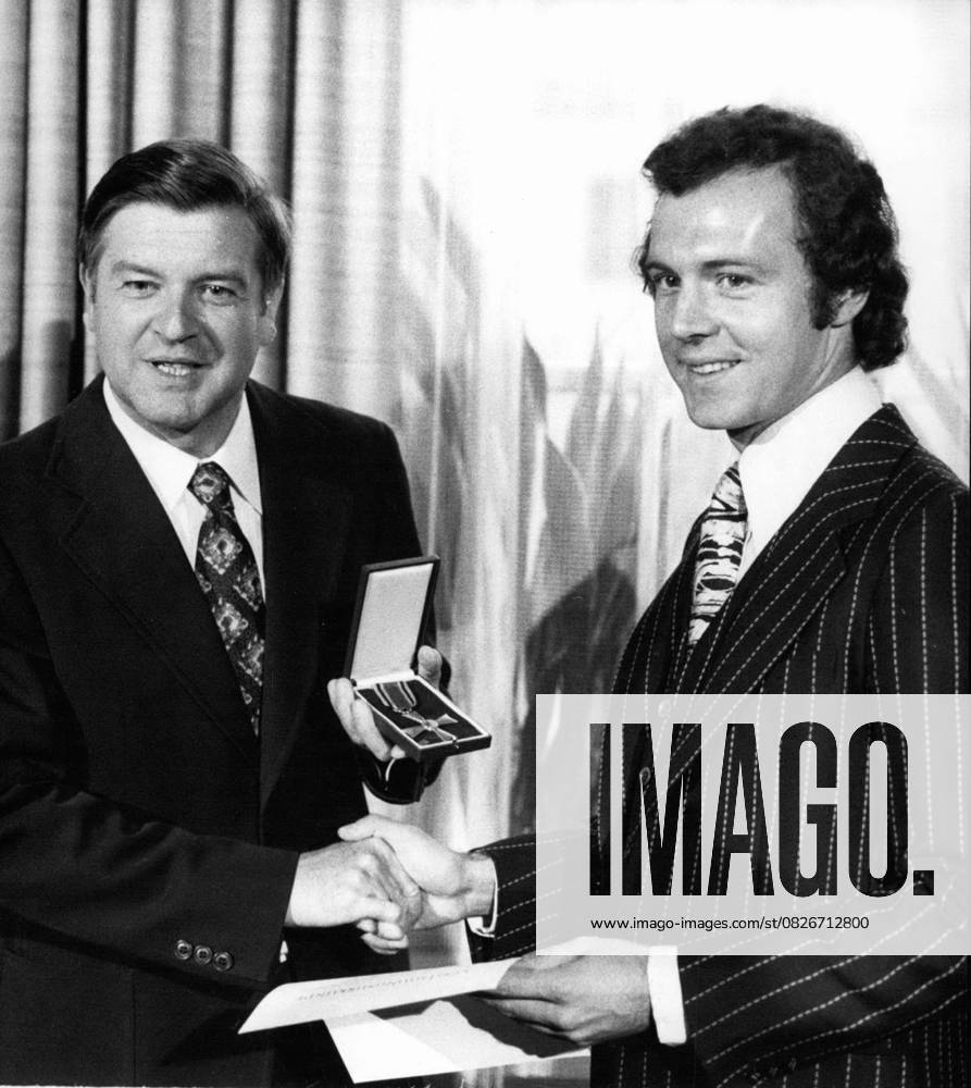Rugby Fußball Sept. 09, 1976 - Fußball-Spieler Franz Beckenbauer wurde mit dem Bundesverdienstkreuz ausgezeichnet.: Franz Beckenbauer (31), der berühmte bayerische Fußballspieler, hat am 16. September 1976 das Bundesverdienstkreuz am Bande erhalten. Der Kapitän des Fußballvereins Bayern München sowie der westdeutschen Nationalmannschaft, die seit 1974 Weltmeister ist, wurde auf Empfehlung des bayerischen Ministerpräsidenten vom Bundespräsidenten mit dem Verdienstkreuz ausgezeichnet. Das Foto zeigt Franz Beckenbauer (r) nach der Verleihung des Verdienstkreuzes durch den bayerischen Kultusminister Hans Maier (l.).