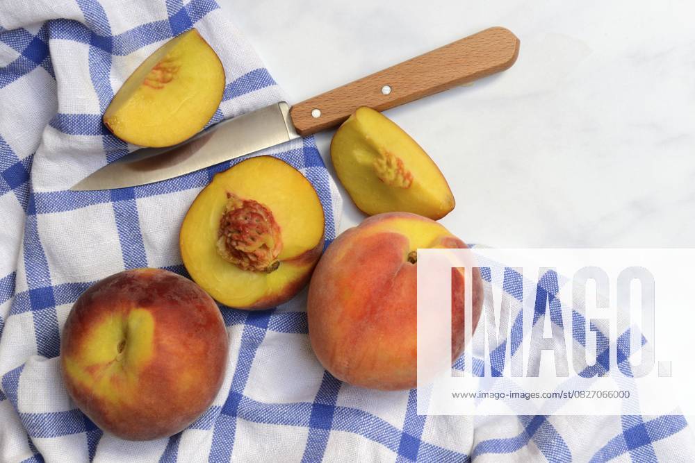 Pfirsich mit Messer auf Küchentuch, Pfirsichhälften, Prunus persica Peach with knife on kitchen towel, peach halves, Prunus persica