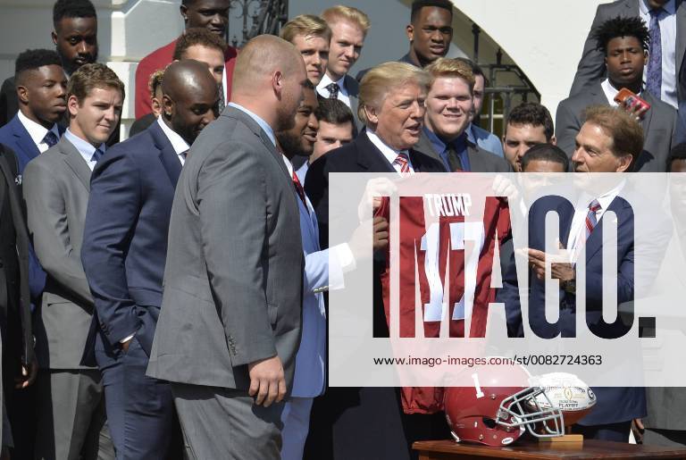 President Donald Trump (C) holds up a jersey presented by University of Alabama Head Coach Nick Saban (R) and players from the NCAA National Champion Crimson Tide football team during a visit to the White House, April 10, 2018, in Washington, DC. WAP20180410599 MIKExTHEILER