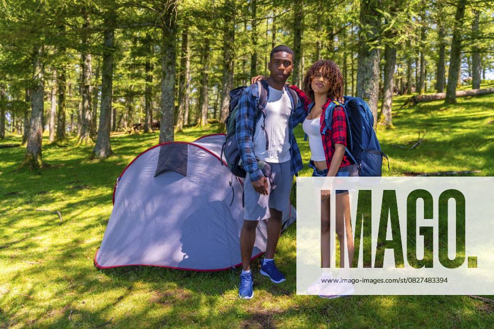 Junge Wanderer posieren zusammen neben ihrem Zelt in einem schönen sonnigen Wald und genießen die Ruhe der Natur während ihres Campingabenteuers Young hikers posing together next to their tent in a beautiful sunny forest, enjoying the tranquility of nature during their camping adventure
