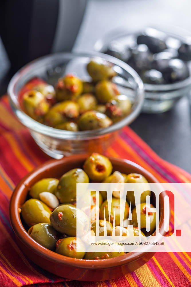 Tapas. Aromatisierte eingelegte Oliven in einer Schale auf einer Serviette. Tapas. Flavored pickled olives in bowl on a kitchen napkin. (License=RF)