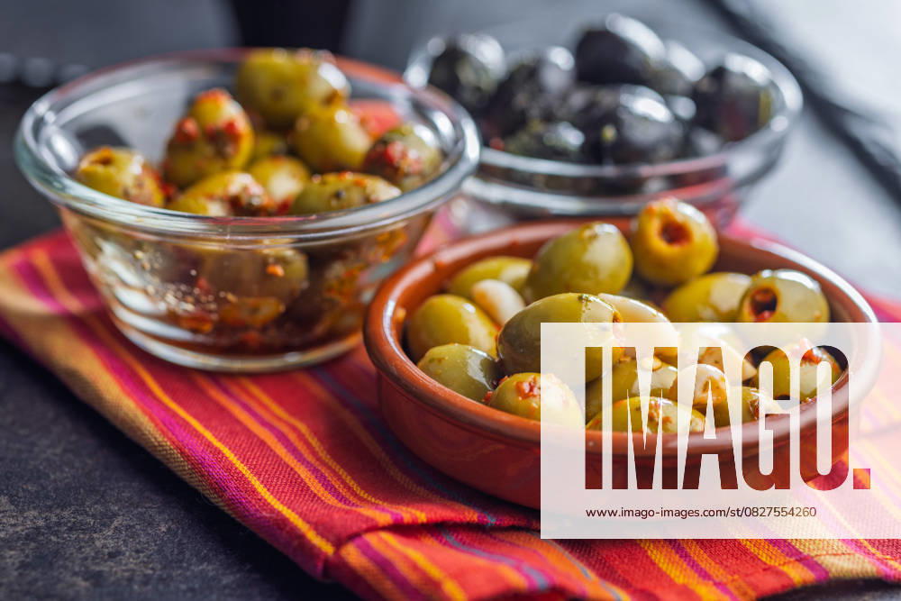 Tapas. Aromatisierte eingelegte Oliven in einer Schale auf einer Serviette. Tapas. Flavored pickled olives in bowl on a kitchen napkin. (License=RF)