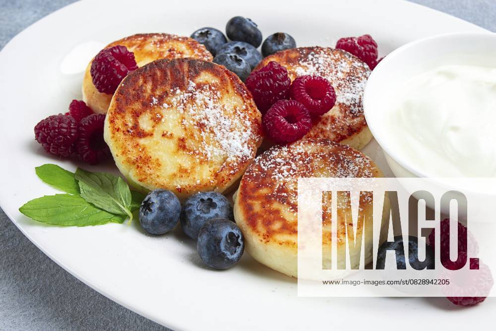 IMAGO Creative, Food, High Protein Frühstück Frühstück, Hüttenkäsekuchen, mit frischen Beeren und saurer Sahne, Draufsicht, Nahaufnahme, ohne Personen Breakfast, cottage cheese cakes, with fresh berries, and sour cream, top view, close-up, no people