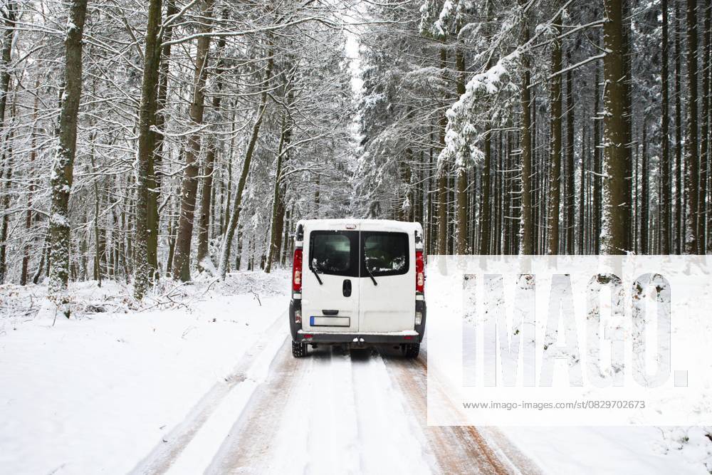 Wohnmobil auf einer Straße durch einen schneebedeckten Wald im Winter, Abenteuerurlaub und Lebensstil in den Wäldern, rutschige Autobahn Camper Van driving on a road through a snow covered forest in winter, adventure vacation and lifestyle in the woodlands, slippery highway