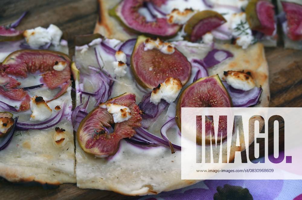 Flammkuchen mit frischen Feigen, Zwiebeln und Ziegenkäse auf einem Holzbrett serviert, Baden-Württemberg, Deutschland Tarte flambée with fresh figs, onions and goat s cheese served on a wooden board, Baden-Württemberg, Germany