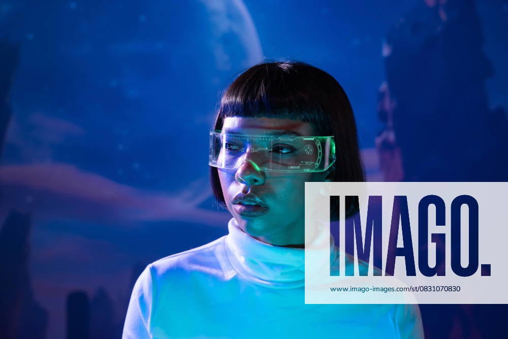 IMAGO Creative, Lifestyle, Gaming MR_ID31144_22470_OrianaDiaz.jpg A Latin woman, wearing futuristic virtual reality glasses, is immersed in a technological experience. The blue ethereal background enhances the sense of advanced digital interaction. Model Released ManuelRuiz_ID31144_1056386_005