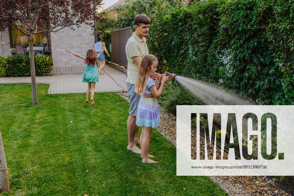 Family gardening together outdoors and watering plants in summer model released, Symbolfoto property released, MDOF02998