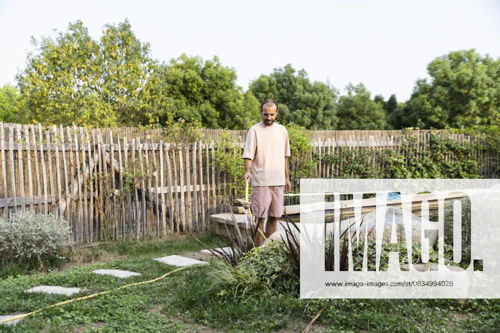 Man watering xerophytic plants in eco-friendly backyard garden model released, Symbolfoto property released, PCLF02598