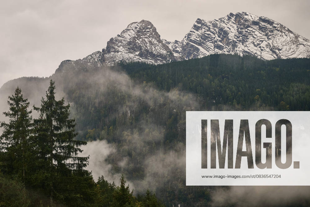 Schönau a. Königssee, Deutschland 08.10.2025: Im Bild: Blick von der Jennerbahn-Bergstation auf die verschneiten Gipfel des Watzmannmassivs mit Watzmannfrau (links) und Watzmann (rechts) in Schönau am Königssee. Nebelschwaden ziehen durch den herbstlichen Bergwald und verleihen der Szenerie eine mystische Stimmung Aufnahme vom 8. Oktober 2025. Bayern