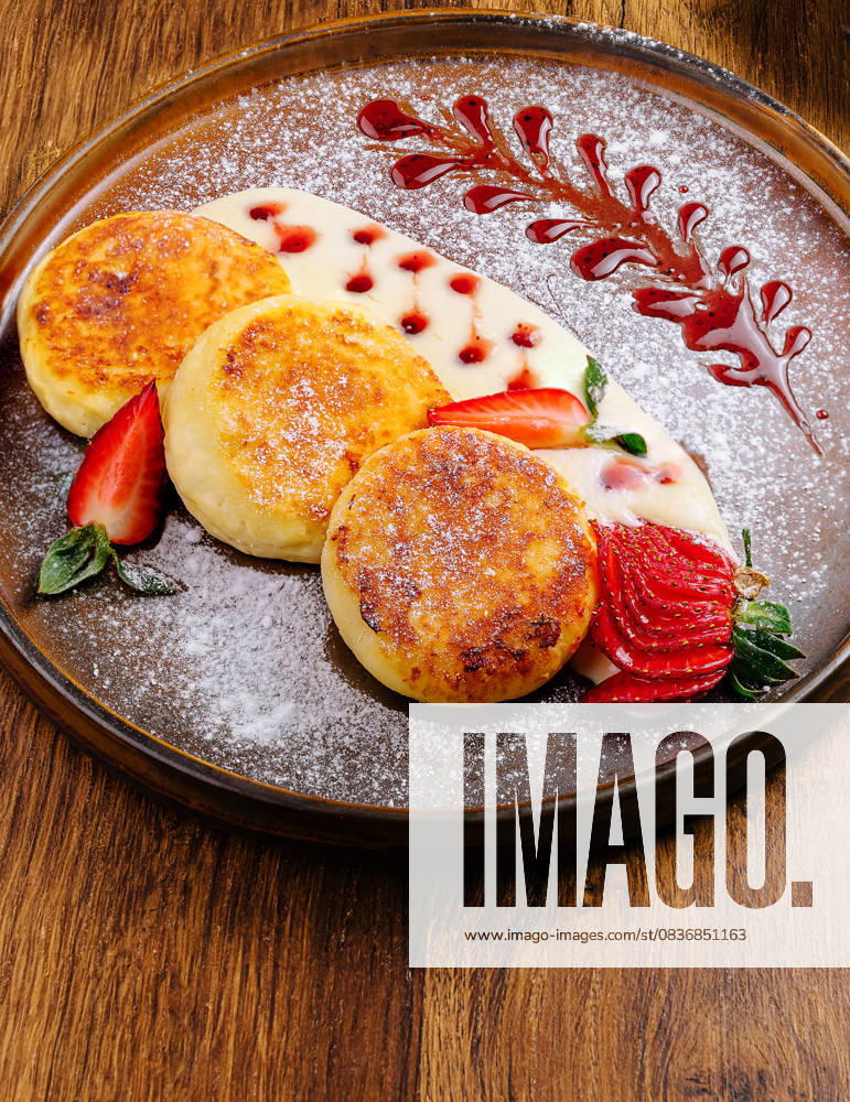 IMAGO Creative, Food, High Protein Frühstück Leckere Hüttenkäsepfannkuchen mit Sahne, Beeren und Puderzucker A gourmet dining experience showcases a vibrant plate of pancakes adorned with strawberries, a succulent burger alongside fries, and colorful grilled skewers on a wooden table. (License=RF)