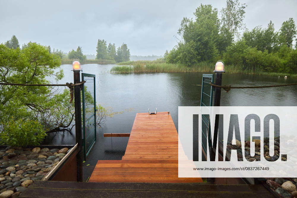 IMAGO Creative, Jahreszeit Sommer, Regen, Sommerregen Serene wooden dock beside calm water during a rainy day Saint Petersburg, Saint Petersburg, Russia R_KNCD251008-1849890-01