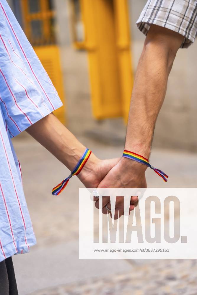 Die Hände des Paares halten sich zusammen, beide Handgelenke mit Regenbogenarmbändern, die Liebe, Stolz und Unterstützung für die lgbtq plus Gemeinschaft symbolisieren und für Gleichheit stehen Couple s hands holding together, both wrists featuring rainbow bracelets, symbolizing love, pride, and support for the lgbtq plus community, representing equality