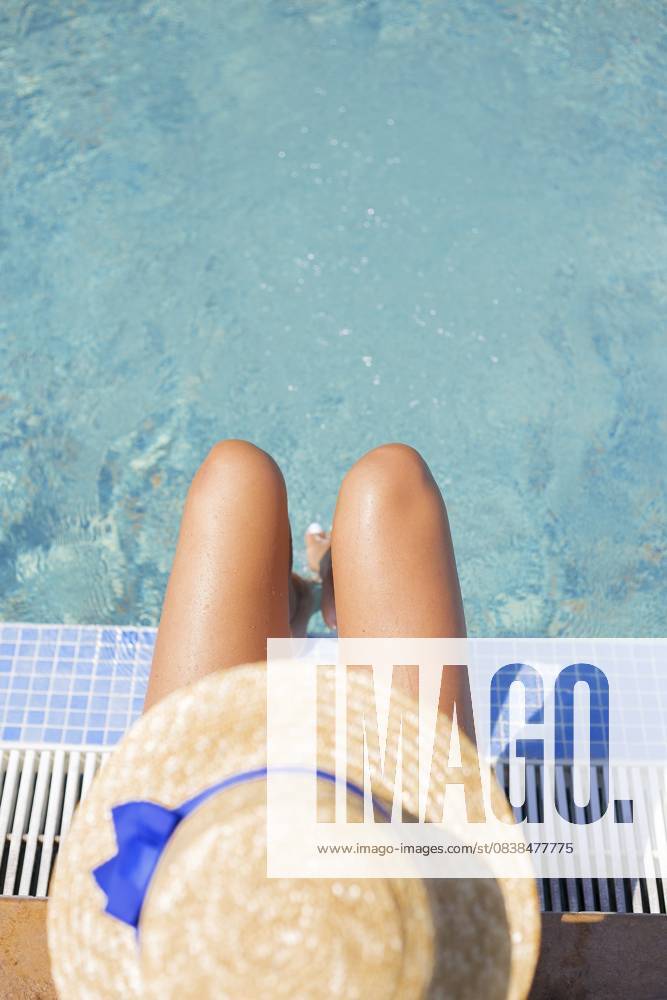 Schönes Mädchen mit Hut in der Nähe eines blauen Pools Sonne, Sommer, Hitze Beautiful girl in a hat near a blue pool - sun, summer, heat