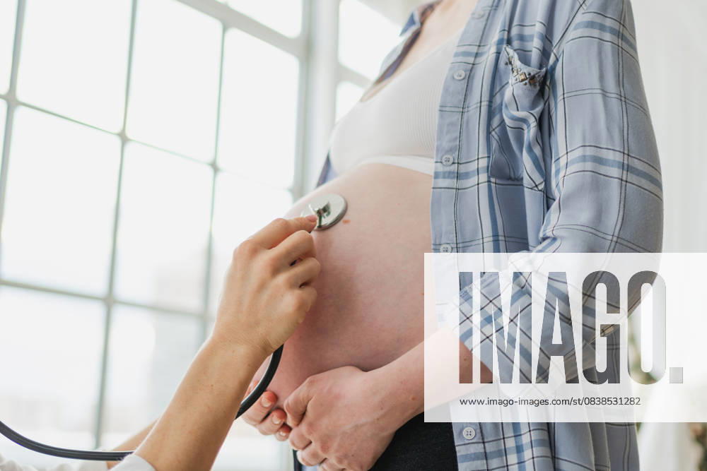 Arzt untersucht schwangere Frau hält Stethoskop in der Nähe von großen Bauch hören Baby Herzschlag. Gynäkologe Arzt Beratung Patientin über Schwangerschaft im Krankenhaus Büro. Besuch beim Arzt medizinischen Checkup. Doctor examining pregnant woman holding stethoscope near big belly listening baby heartbeat. Gynecologist doctor consulting patient about pregnancy in hospital office. Visit to doctor medical checkup (License=RF) ,model released, Symbolfoto