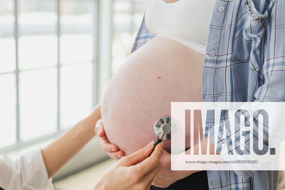 Arzt untersucht schwangere Frau hält Stethoskop in der Nähe von großen Bauch hören Baby Herzschlag. Gynäkologe Arzt Beratung Patientin über Schwangerschaft im Krankenhaus Büro. Besuch beim Arzt medizinischen Checkup. Doctor examining pregnant woman holding stethoscope near big belly listening baby heartbeat. Gynecologist doctor consulting patient about pregnancy in hospital office. Visit to doctor medical checkup (License=RF) ,model released, Symbolfoto