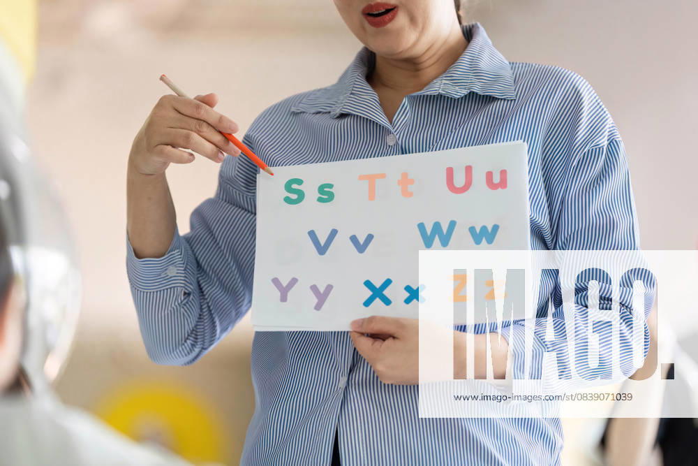 Zurück zur Schule: Lehrer motivieren junge Schüler zum Lernen des Alphabets An educator uses a colorful chart to teach young children the alphabet in a lively classroom setting, promoting early literacy. (License=RF) ,model released, Symbolfoto
