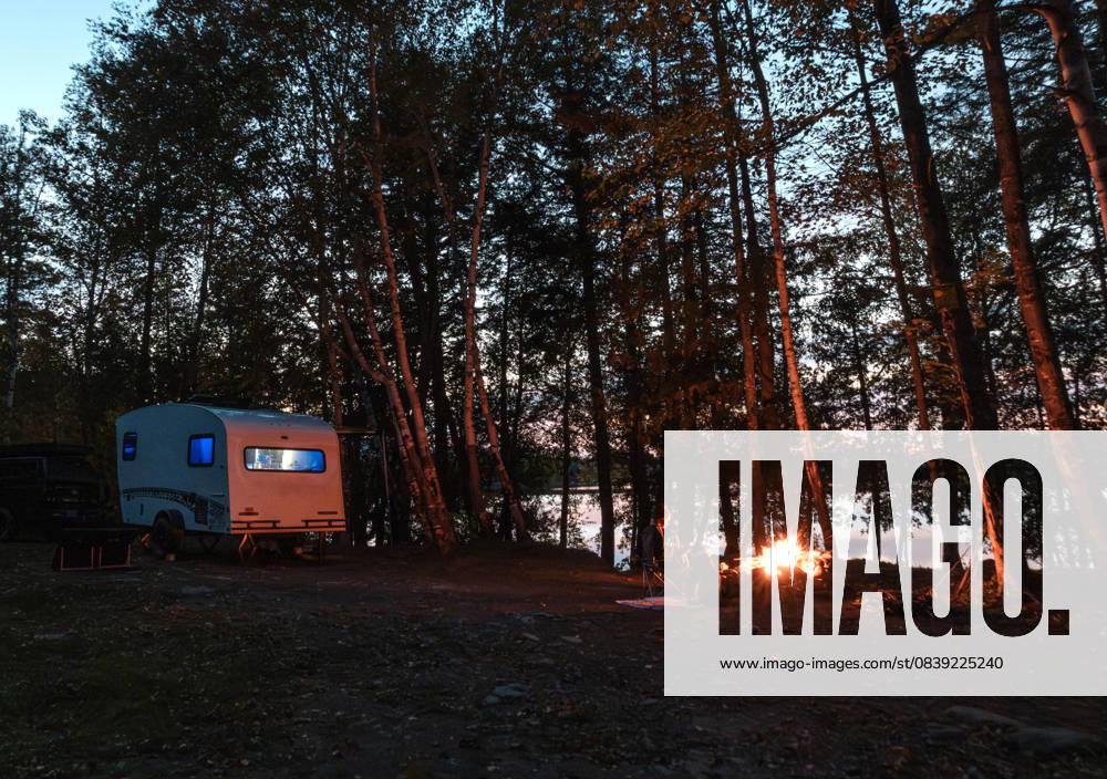 RV Camper on shore of lake with campfire at dusk, Maine The Forks, Maine, United States CR_SSNF2511012D-1872080-01 ,model released, Symbolfoto