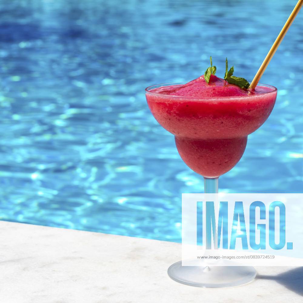 Ein lebendiger Erdbeer Daiquiri an einem erfrischenden Pool an einem sonnigen Tag, der ein Gefühl von Entspannung und tropischer Flucht hervorruft A vibrant strawberry daiquiri by a refreshing pool on a sunny day, evoking a sense of relaxation and tropical escape