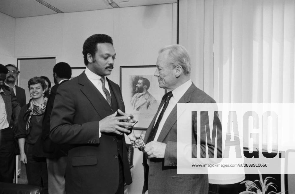 Der US-amerikanische Bürgerrechtler Jesse Jackson und der SPD-Ehrenvorsitzende Willy Brandt im Gespräch am 9. Mai 1985 in Bonn. Die Aufnahme zeigt beide Politiker in angeregtem Austausch in einem Büroraum, umgeben von Begleitpersonen und Presse. Im Hintergrund ein Porträt von Friedrich Engels. Bonn Nordrhein-Westfalen Deutschland