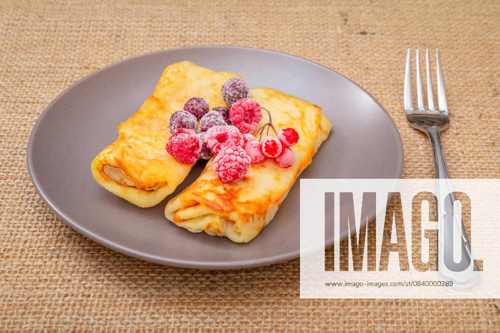 IMAGO Creative, Food, High Protein Frühstück Homemade pancakes and frozen raspberries on plate. Homemade pancakes topped with frozen raspberries and blackberries on the plate with the fork on the sackcloth., 63124372.jpg RECORD DATE NOT STATED