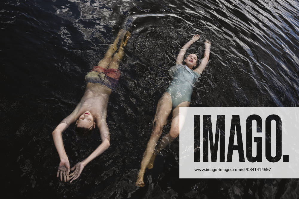 Teens floating and smiling in summer lake wearing swimsuits model released, Symbolfoto, EYAF03632