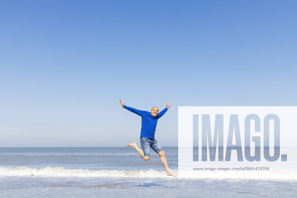 Man jumping for joy on the beach with blue sky and sea model released, Symbolfoto, GWF08396