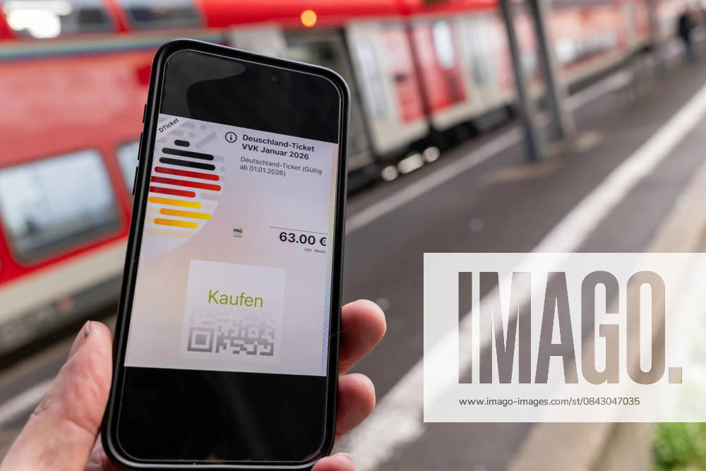Deutschlandticket mit neuem Preis am Bahnhof 17.12.25, Limburg: Symbolfoto, Illustrationsbild, Symbolbild, Illustrationsfoto, Alltagsszene Ein Smartphone zeigt das digitale Deutschlandticket mit einem Preis von 63 Euro. Das Mobiltelefon wird auf einem Bahnsteig gehalten, im Hintergrund ist ein roter Zug unscharf zu sehen. Das Bild steht im Zusammenhang mit der geplanten Preiserhöhung des Deutschlandtickets zum 1. Januar 2026 sowie mit dem öffentlichen Nahverkehr und dem Bahnverkehr in Deutschland. Limburg Hessen
