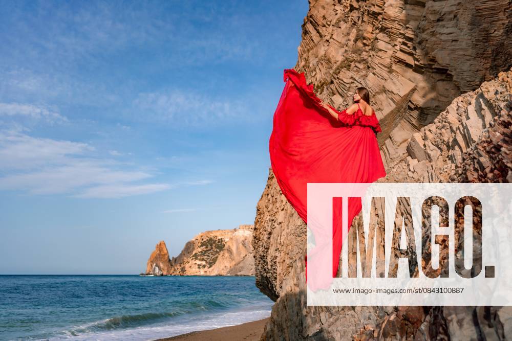 Woman sea red dress. Woman with long hair on a sunny seashore in a red flowing dress, back view, silk fabric waving in the wind. Against the backdrop of the blue sky and mountains on the seashore. woman sea red dress. Woman with long hair on a sunny seashore in a red flowing dress, back view, silk fabric waving in the wind. Against the backdrop of the blue sky and mountains on the seashore, model released, , 61526700.jpg RECORD DATE NOT STATED