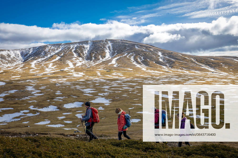 Hikers on a mountain trail. Guarcino (FR), Italy - December 21, 2025: A group of hikers in single file walk along a mountain trail, with the partially snow-capped peaks of the Lazio Apennines in the background. Guarcino FR Italy