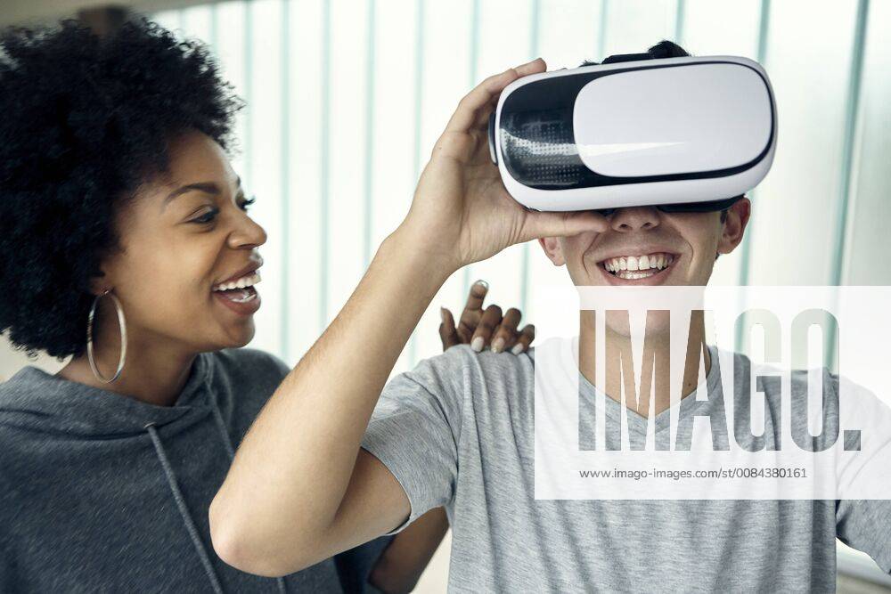 Young man using virtual reality simulator with friend