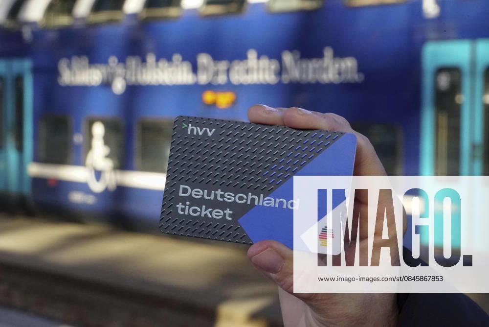 Cntv: Deutschlandtiket in der Hand vor HVV Bus und Bahnen Deutscxhe Bahn Deutschlandticket ist ein monatliches Abonnement für den gesamten deutschen ÖPNV OEPNV oeffentlichen Nahverkehr Busse, Straßenbahnen, U-Bahnen, S-Bahnen, REs, RB). Es kostet seit Januar 2026 63,00 Euro pro Monat und Fahrgast und gilt deutschlandweit Hamburg Germany