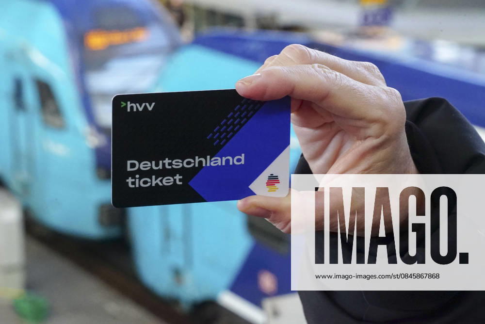 Cntv: Deutschlandtiket in der Hand vor HVV Bus und Bahnen Deutscxhe Bahn Deutschlandticket ist ein monatliches Abonnement für den gesamten deutschen ÖPNV OEPNV oeffentlichen Nahverkehr Busse, Straßenbahnen, U-Bahnen, S-Bahnen, REs, RB). Es kostet seit Januar 2026 63,00 Euro pro Monat und Fahrgast und gilt deutschlandweit Hamburg Germany