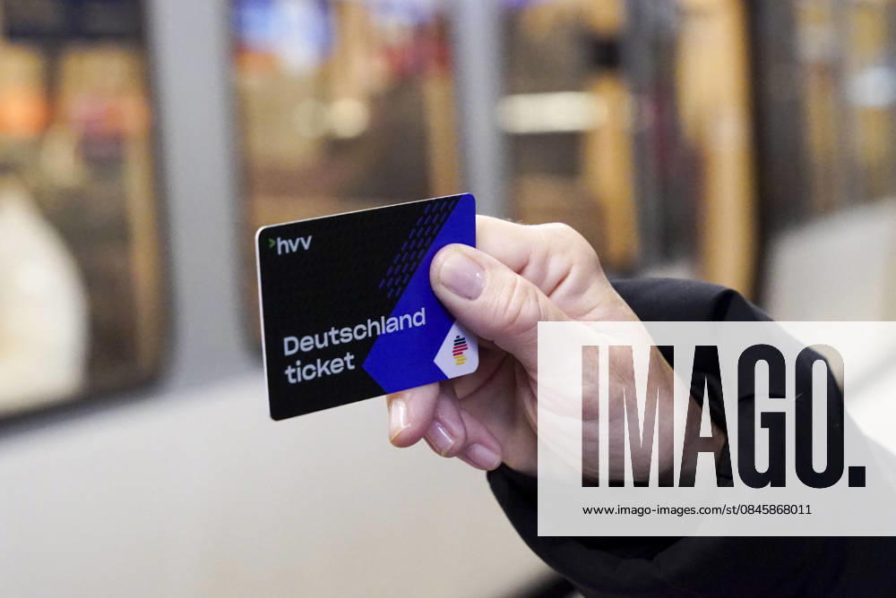 Cntv: Deutschlandtiket in der Hand vor HVV Bus und Bahnen Deutscxhe Bahn Deutschlandticket ist ein monatliches Abonnement für den gesamten deutschen ÖPNV OEPNV oeffentlichen Nahverkehr Busse, Straßenbahnen, U-Bahnen, S-Bahnen, REs, RB). Es kostet seit Januar 2026 63,00 Euro pro Monat und Fahrgast und gilt deutschlandweit Hamburg Germany