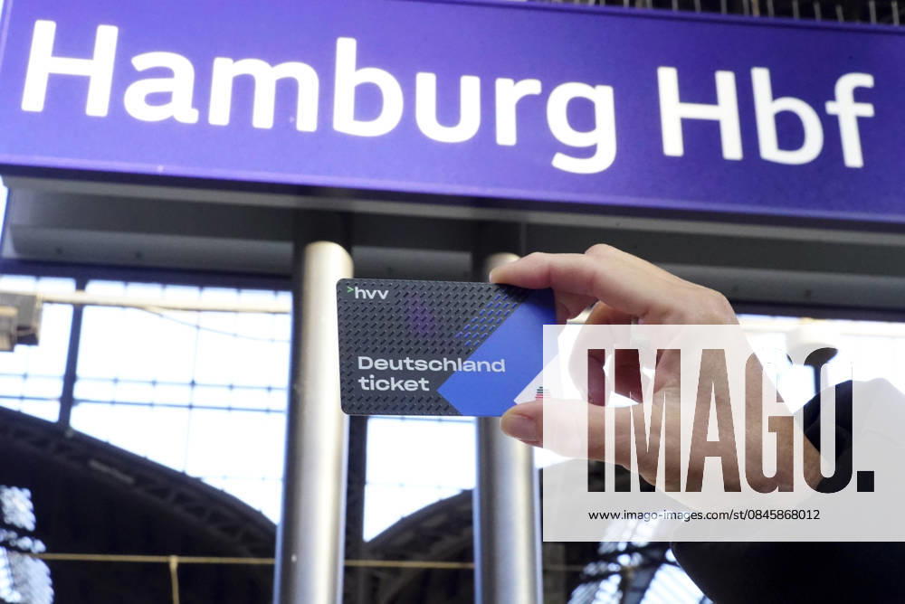 Cntv: Deutschlandtiket in der Hand vor HVV Bus und Bahnen Deutscxhe Bahn Deutschlandticket ist ein monatliches Abonnement für den gesamten deutschen ÖPNV OEPNV oeffentlichen Nahverkehr Busse, Straßenbahnen, U-Bahnen, S-Bahnen, REs, RB). Es kostet seit Januar 2026 63,00 Euro pro Monat und Fahrgast und gilt deutschlandweit Hamburg Germany