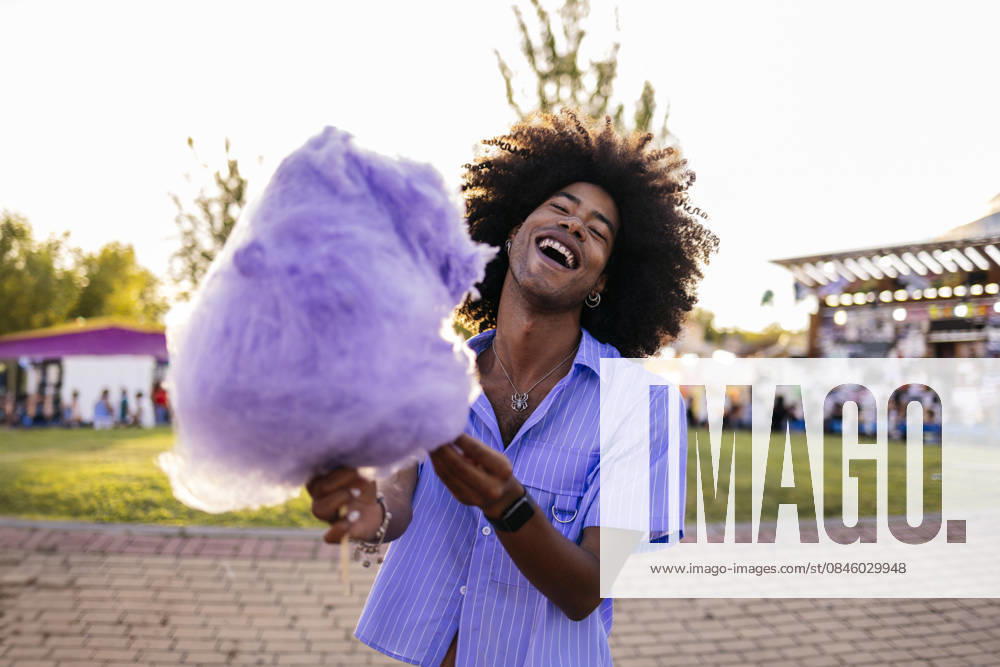Cheerful young man holding cotton candy and enjoying in amusement park model released, Symbolfoto, ALZF00805