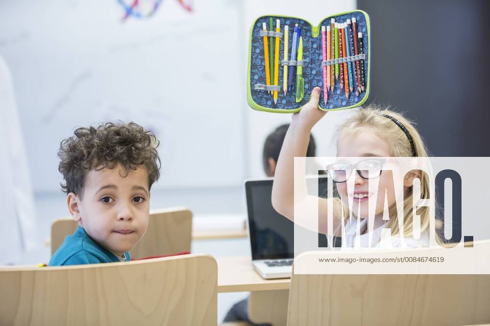 Portrait of schoolboy and schoolgirl with laptop and pencil case in class model released Symbolfoto property released WESTF24227