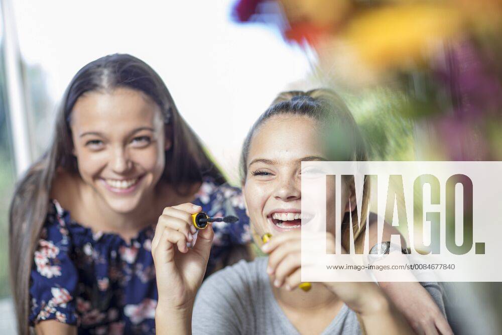 Happy teenage girl watching friend applying mascara model released Symbolfoto property released ZEF15650