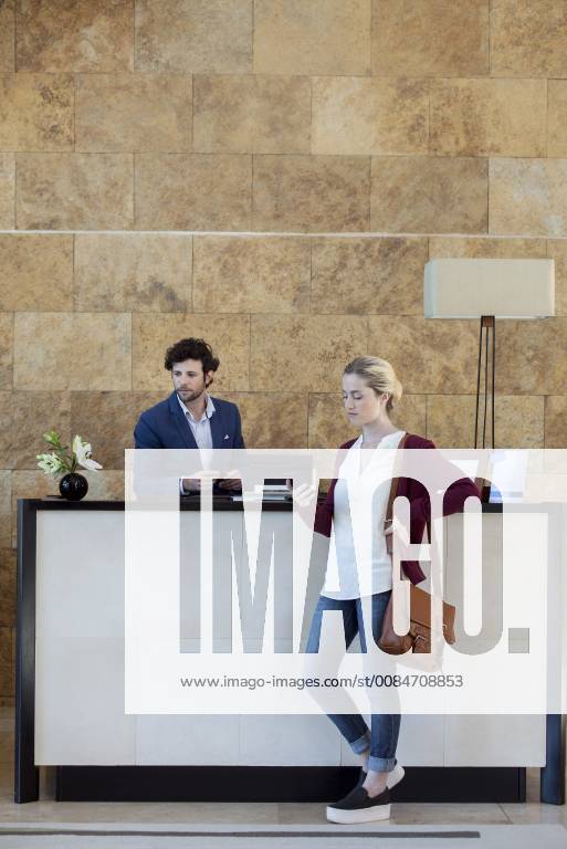 Woman looking at smartphone while waiting at reception desk