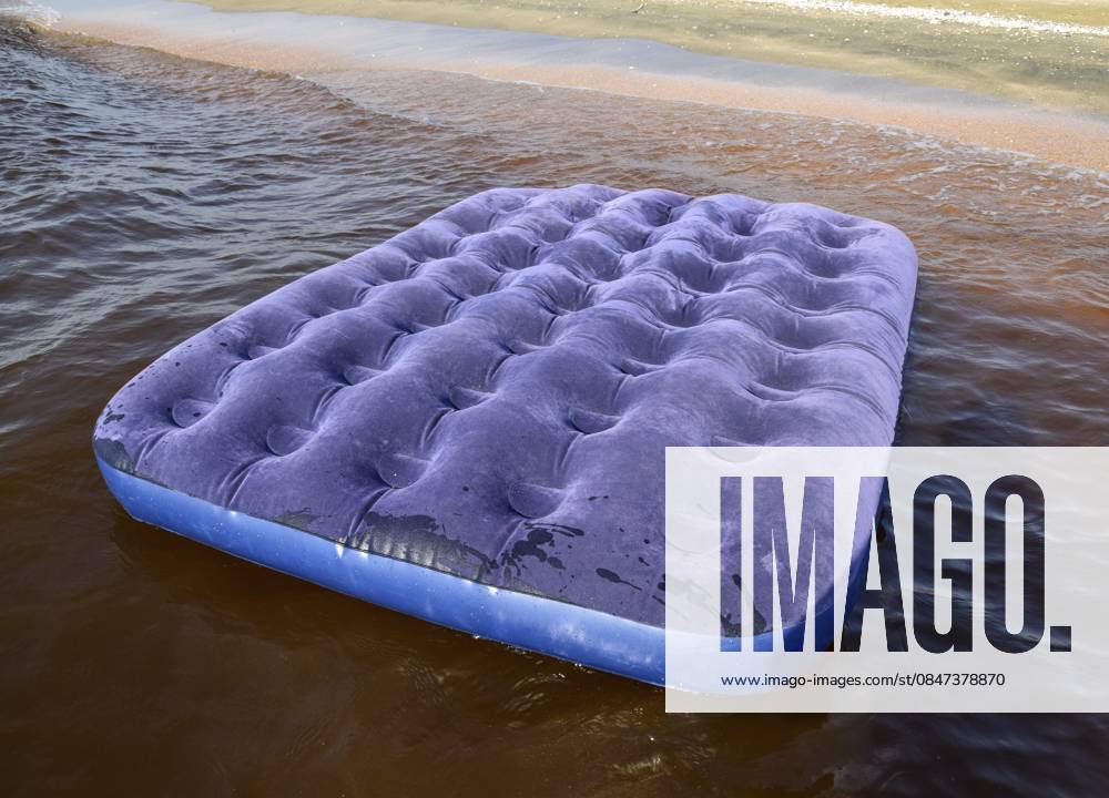 Blaue aufblasbare Matratze, die im Teich schwimmt. Eine aufblasbare Matratze am Strand Blue inflatable mattress swimming in the pond. An inflatable mattress on the beach