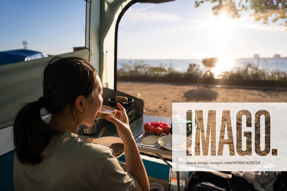 Woman enjoying breakfast while camping in Portugal A woman enjoys a peaceful breakfast in her tent while camping by a scenic seaside in Portugal. The scene captures the essence of outdoor adventure and tranquility. Model Released JuanAlbertoRuiz_ID32581_1110054_035